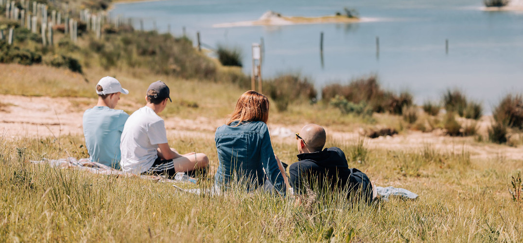 A group of friends sat on the grass by a lake