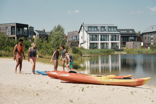 A family on a sandy lakeside beach with two kayaks
