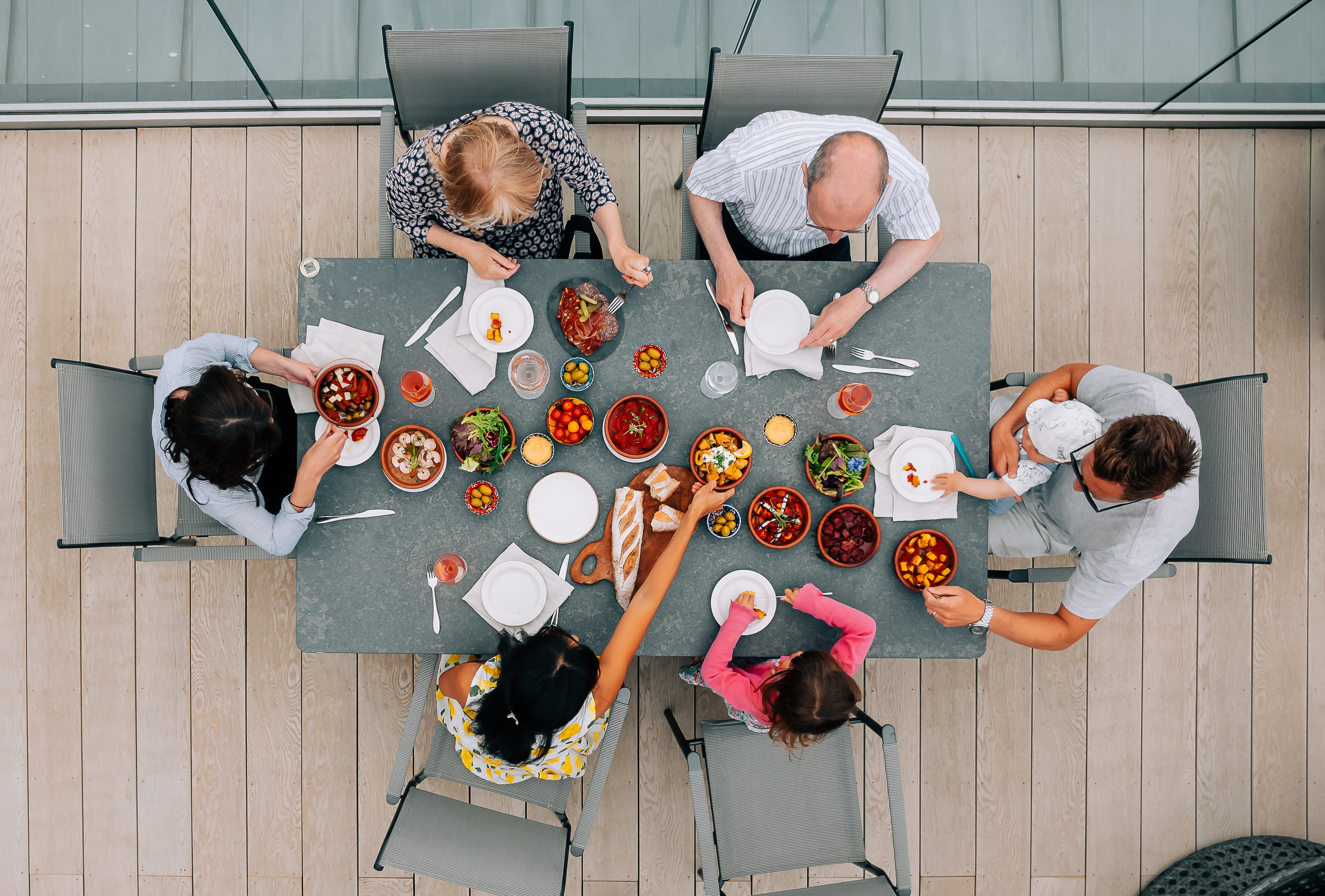 An aerial view of 6 adults sat at a table eating tapas